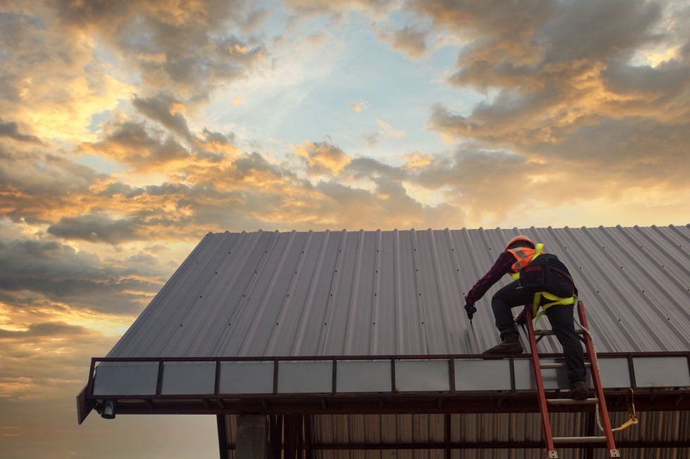Stock image of worker installing a new white metal roof